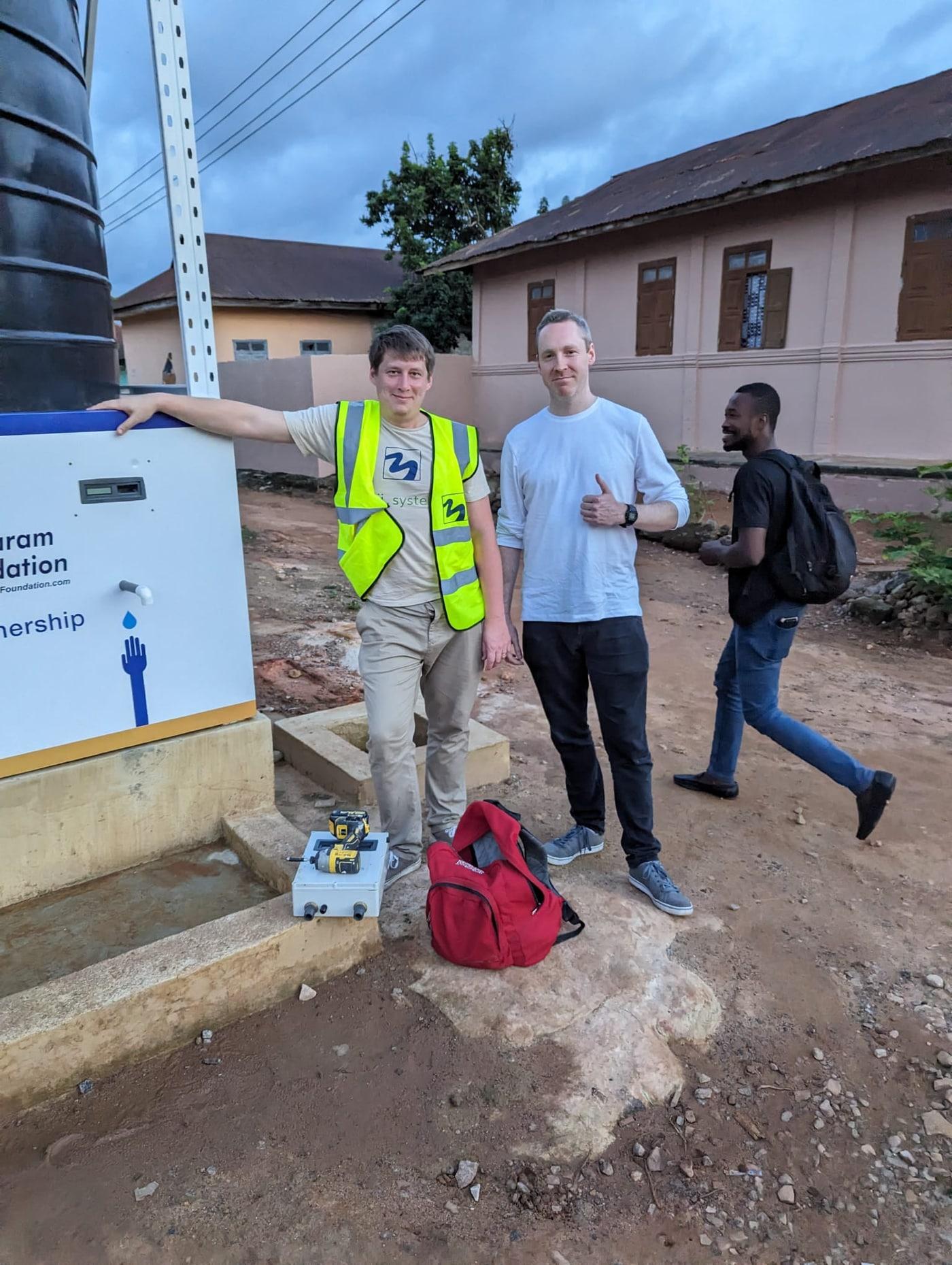 Maji Systems team members beside an installed water dispenser during a partner site visit