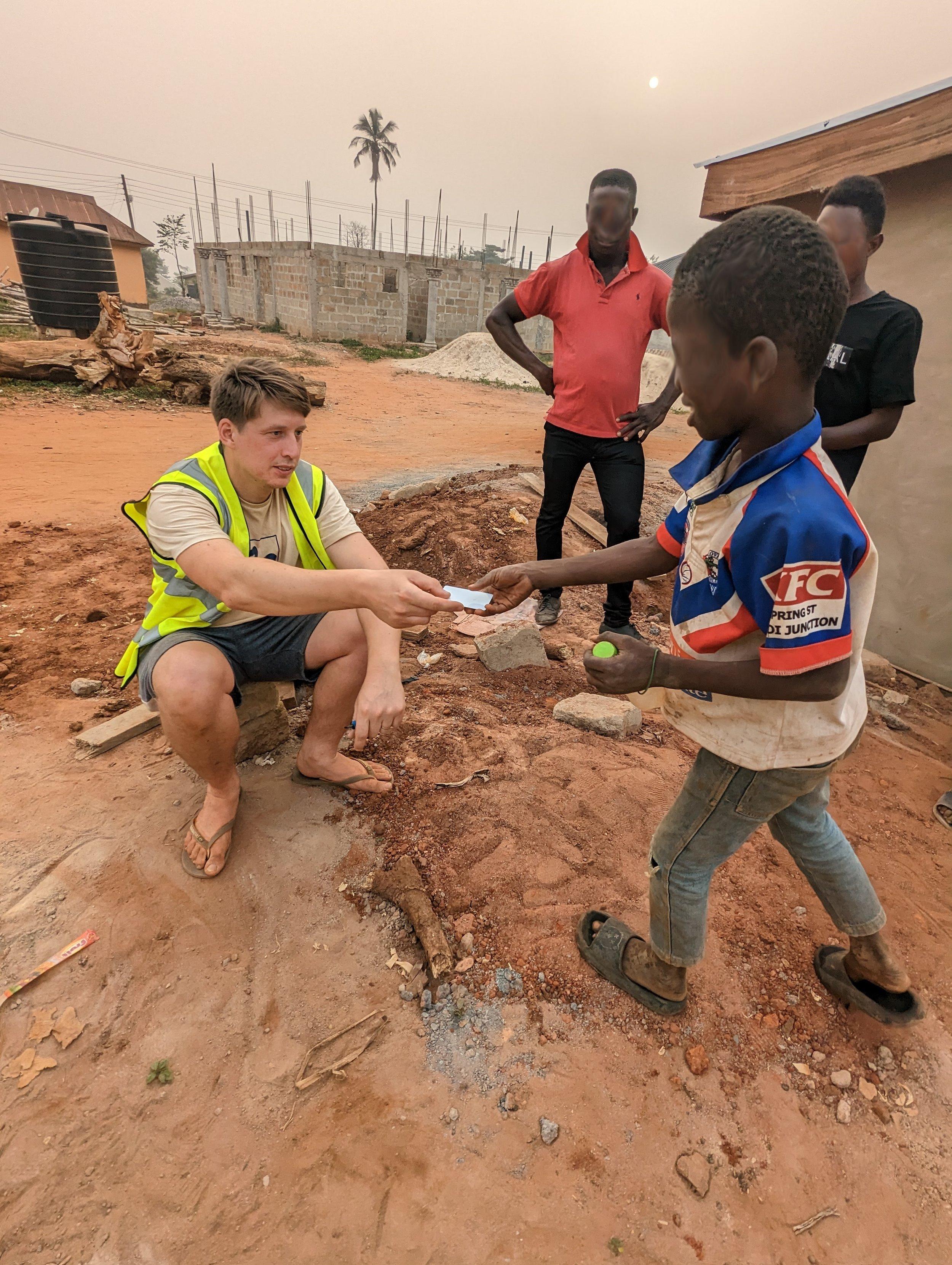 A Maji Systems team member handing a prepaid WaterCard to a resident in the Ashanti Region, Ghana