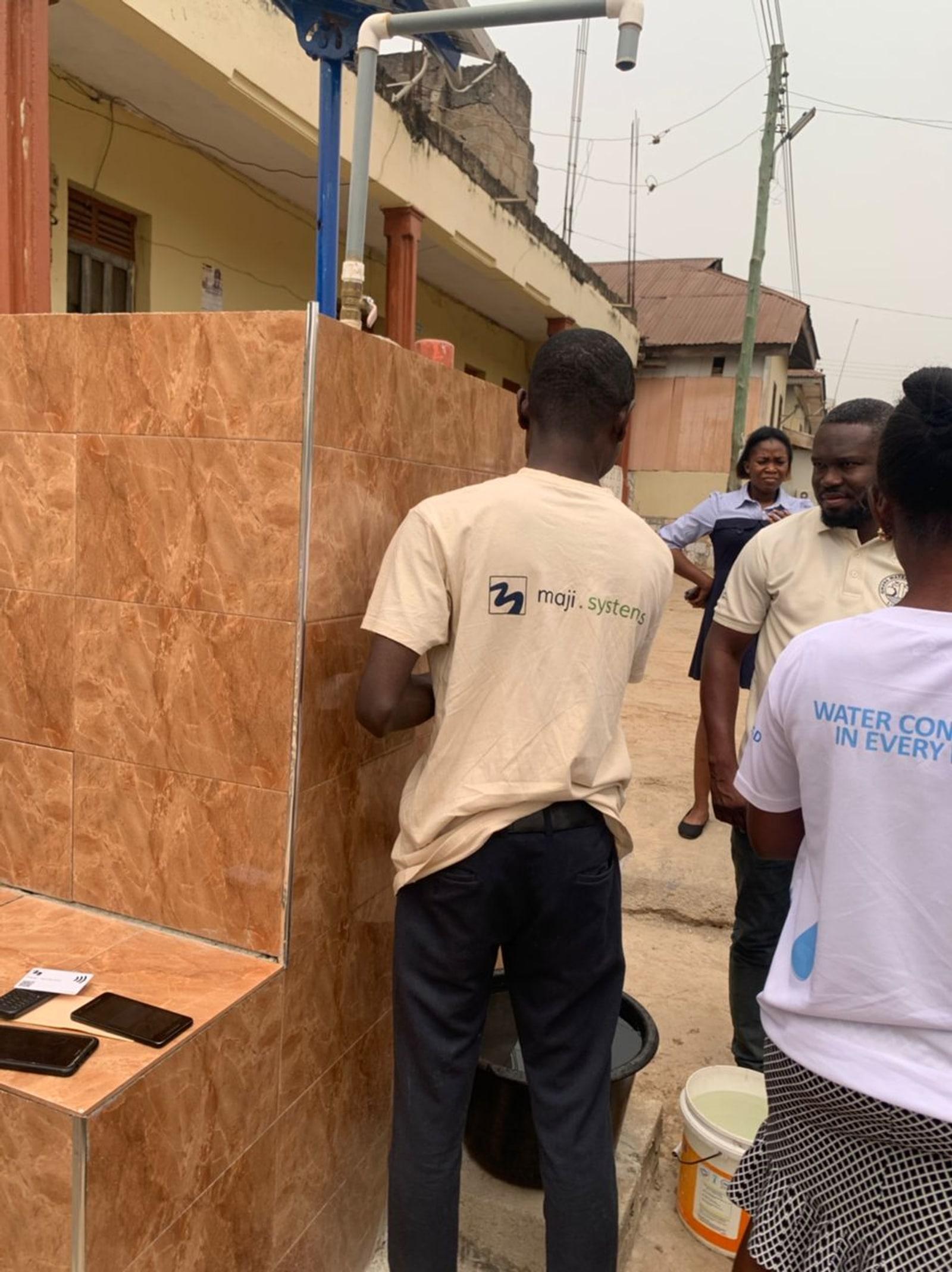 A flush-mounted Maji Community Dispenser panel built into a corner wall in Kumasi, Ghana
